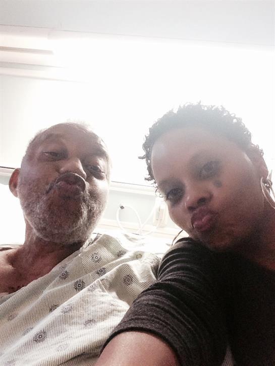 Two individuals share a light-hearted moment while posing in a hospital.