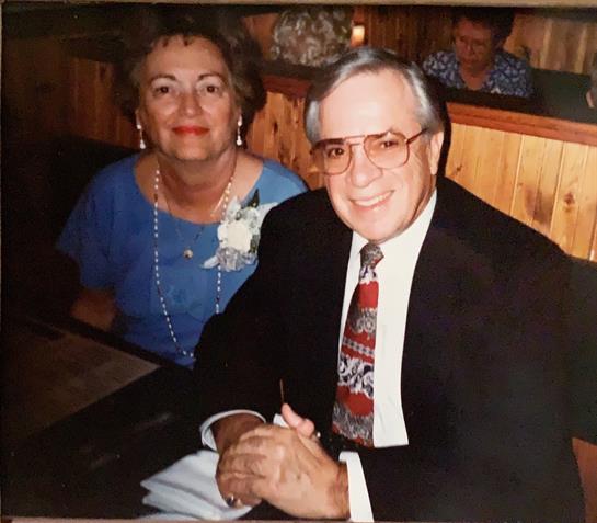 A couple smiles at a table, celebrating with friends in a cozy restaurant.