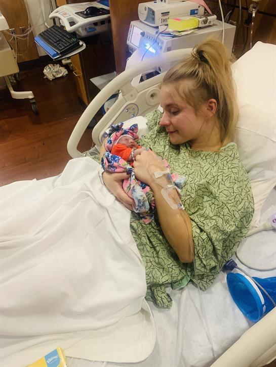 A new mother cradles her infant while resting in a hospital bed, filled with joy and love.