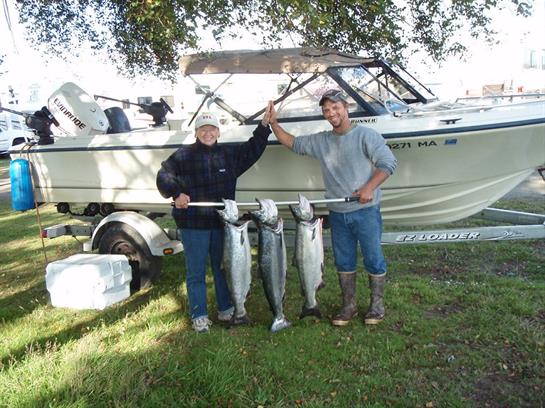 Two anglers celebrate their successful fishing trip, proudly showing off their catch beside a boat.
