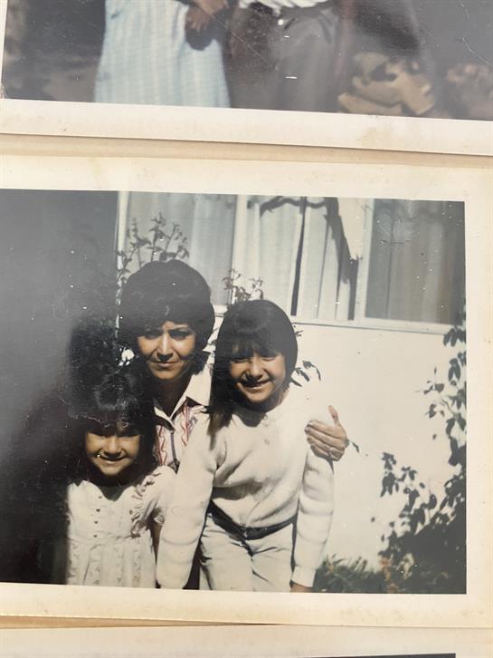 Three smiling kids stand with an adult outside a house, capturing a joyful moment.