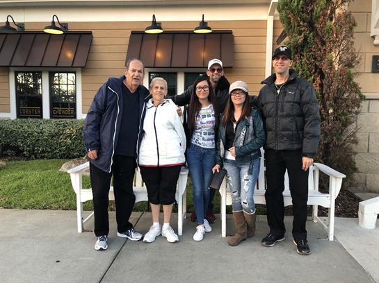 A group stands outside a restaurant, smiling and dressed casually for an evening hangout.