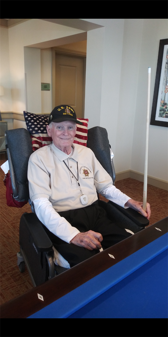 A veteran sits comfortably in an adaptive chair, showcasing an American flag and his service.