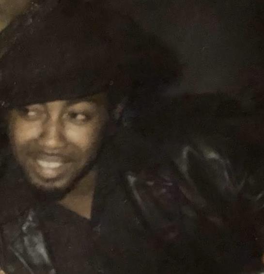 A man smiles while engaging with friends during an energetic night out in a lively atmosphere.