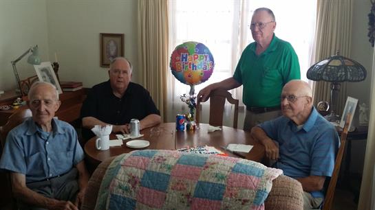 Friends gather around a table to celebrate a birthday with cake and cheerful decorations.