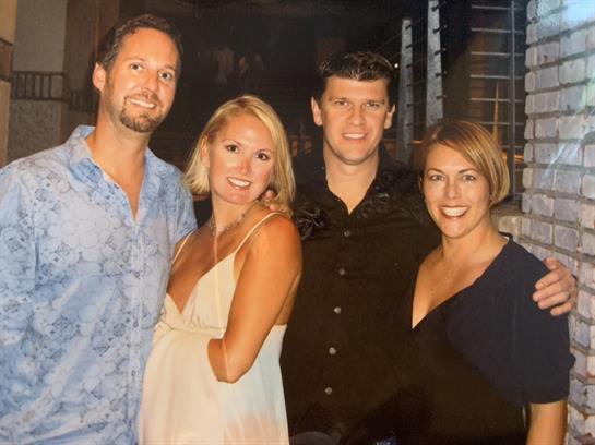 Four friends pose together, smiling and dressed for a lively evening in the city.