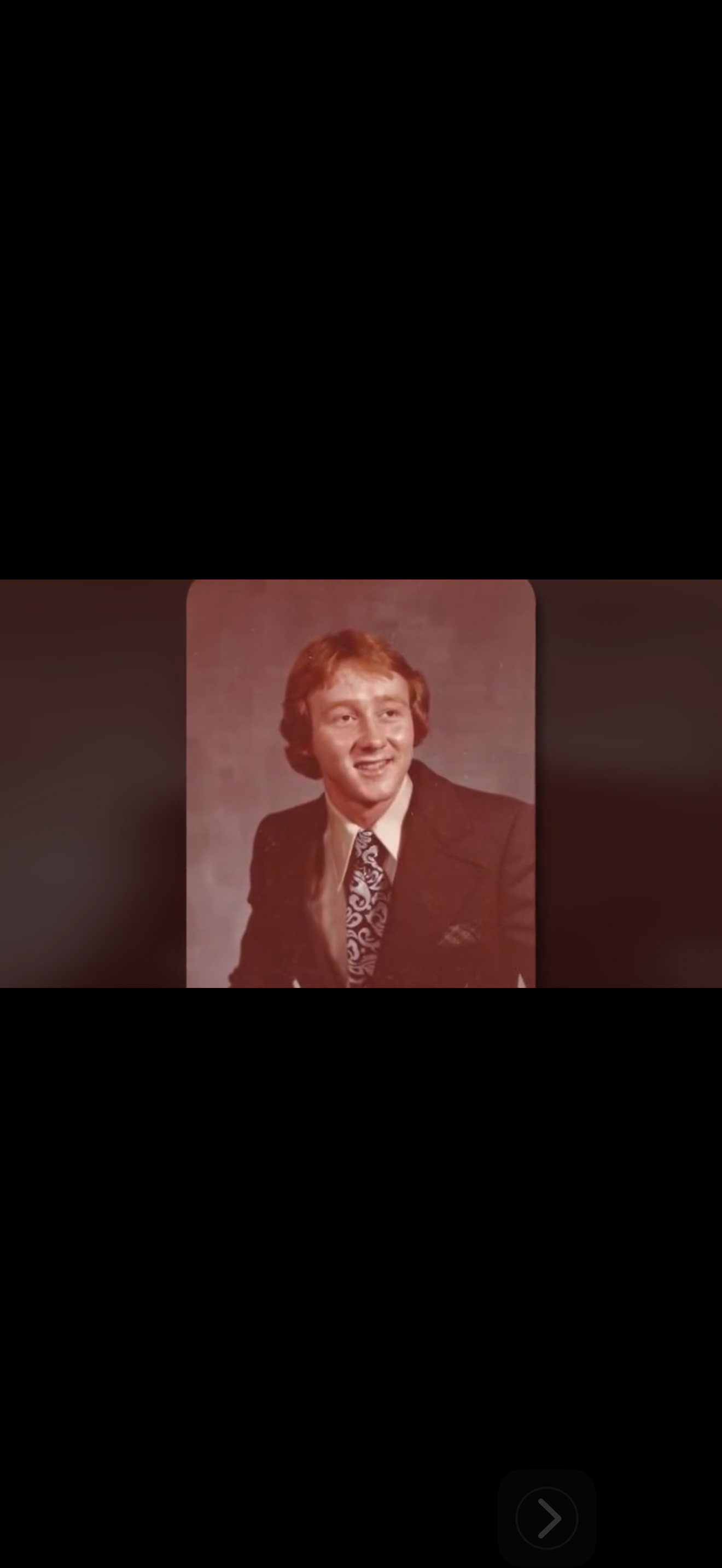 Man wearing a suit and tie smiles confidently in a vintage studio setting capturing a classic look.