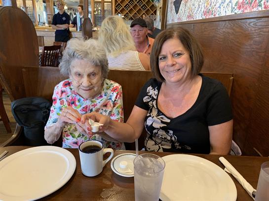 Cheerful interaction between two women sharing a sweet moment while dining in a busy restaurant.