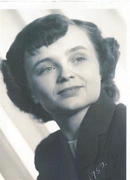 A young woman smiles softly while posing for a portrait in a simple background.