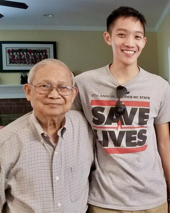 A young man smiles alongside his elderly relative in a cheerful setting, showcasing family love.