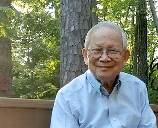 An elderly man enjoys a peaceful moment outdoors, surrounded by trees and nature.