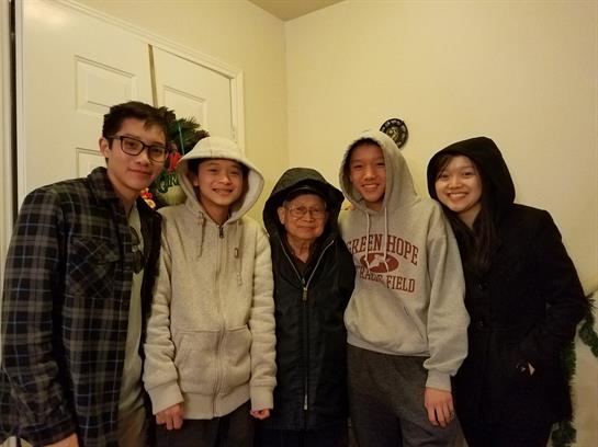 Family members pose together, wearing hoodies, radiating warmth and happiness in their cozy home.