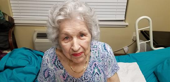 A cheerful elderly woman sits comfortably at home, enjoying a relaxing moment.
