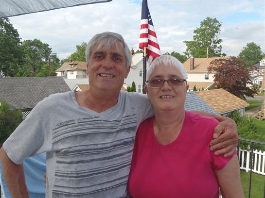 Two friends smile and pose together during a bright day in their neighborhood's backyard.