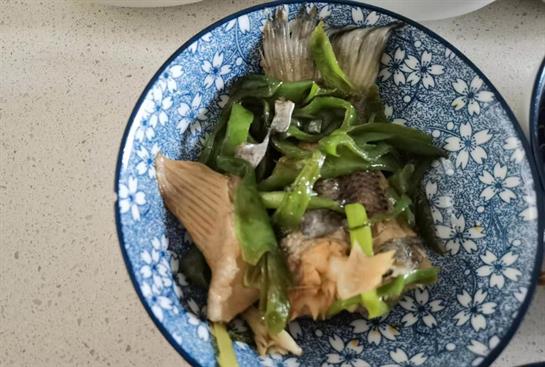 Fish is served with green vegetables on a decorative blue plate, showcasing culinary art.