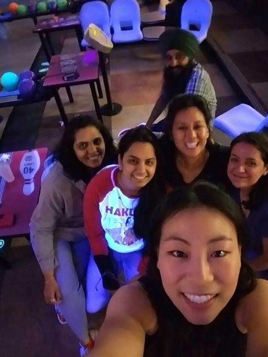 Friends gather and smile together at a bowling alley, enjoying their time in a lively environment.