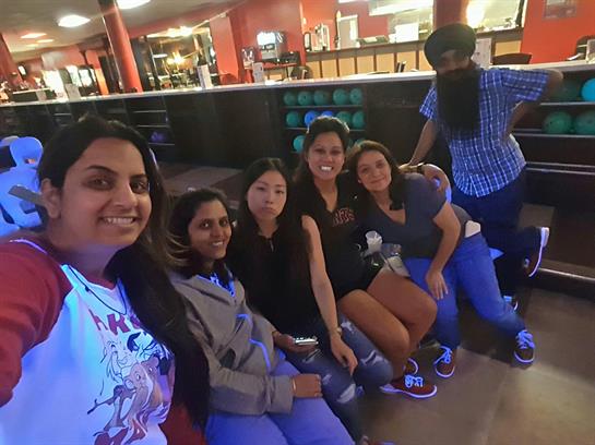 Group of friends sitting together, having fun at a bowling alley during the evening.
