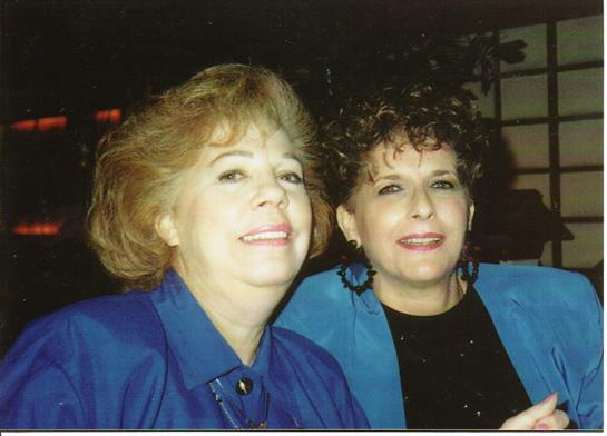 Two women in stylish blue outfits are smiling for a photo, enjoying a memorable evening.