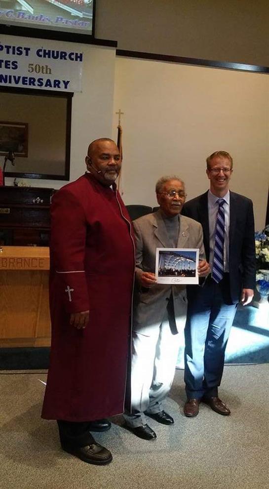 Community members celebrate as an elderly man is honored for his achievements and contributions.