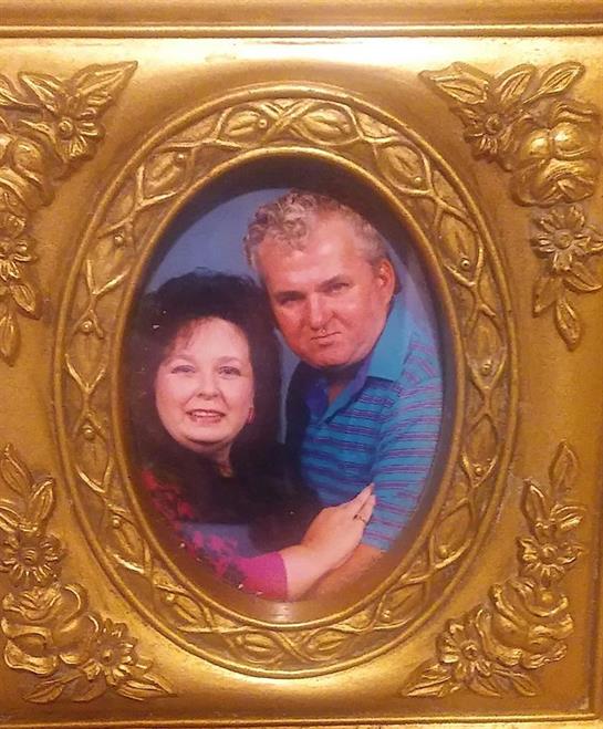 A couple poses together, displaying their love and happiness in an ornate golden frame.