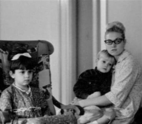 Two children and a caregiver sit closely in a cozy room, showcasing affection and nostalgia.