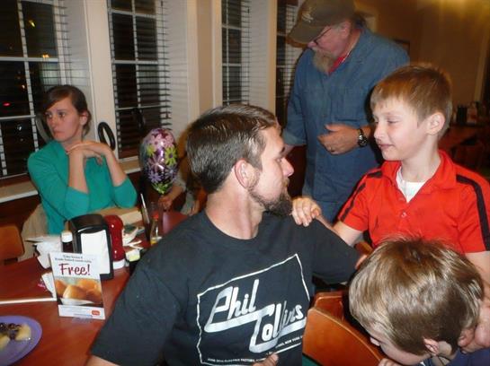 A lively family gathering features children interacting while adults share joyful moments at dinner.
