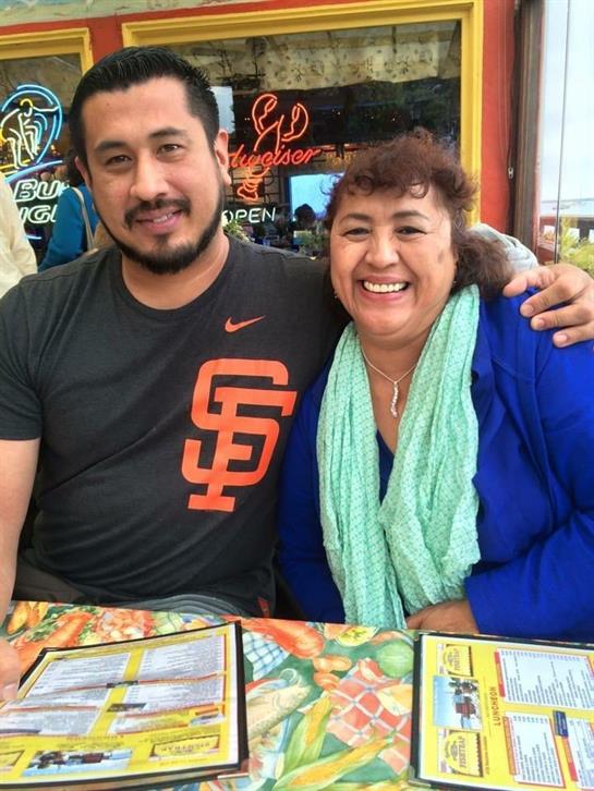 Two friends smile warmly while enjoying their time at a lively restaurant with colorful decor.