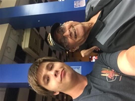 Two family members share smiles while attending a vibrant event in a large indoor venue.