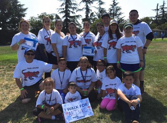 Friends and families gather at the park wearing matching shirts for a charity walk event.