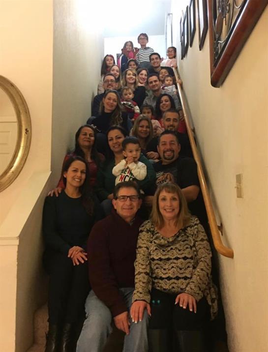 A large family poses happily on a staircase, showcasing their unity and joy in a warm environment.