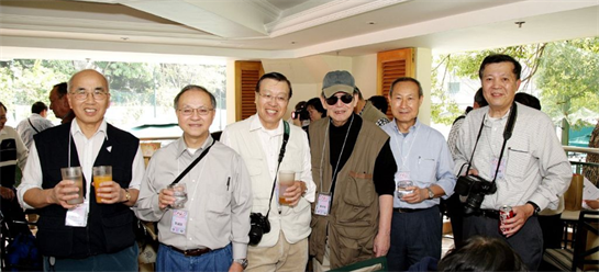 A group of four men shares laughter and drinks, enjoying a sunny afternoon gathering together.