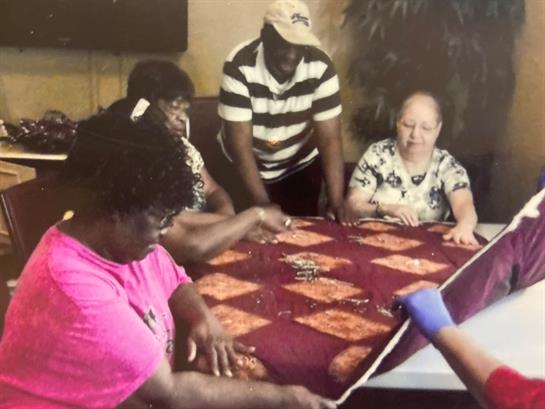 Friends gather around a table to play a game, sharing laughter and conversation during the evening.