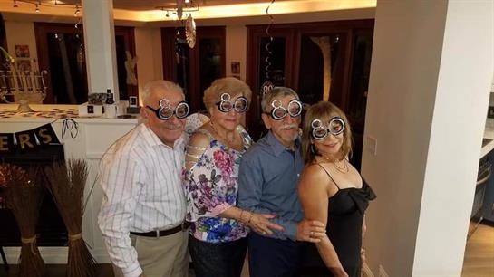 Four friends celebrate in style, sporting quirky glasses at an elegant venue.