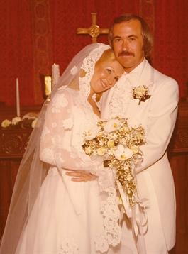Newlywed couple embraces joyfully, surrounded by floral arrangements and candles inside a chapel.