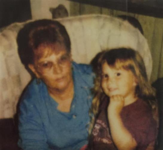 An older woman and a young girl are seated together, sharing a moment in a warm living room.