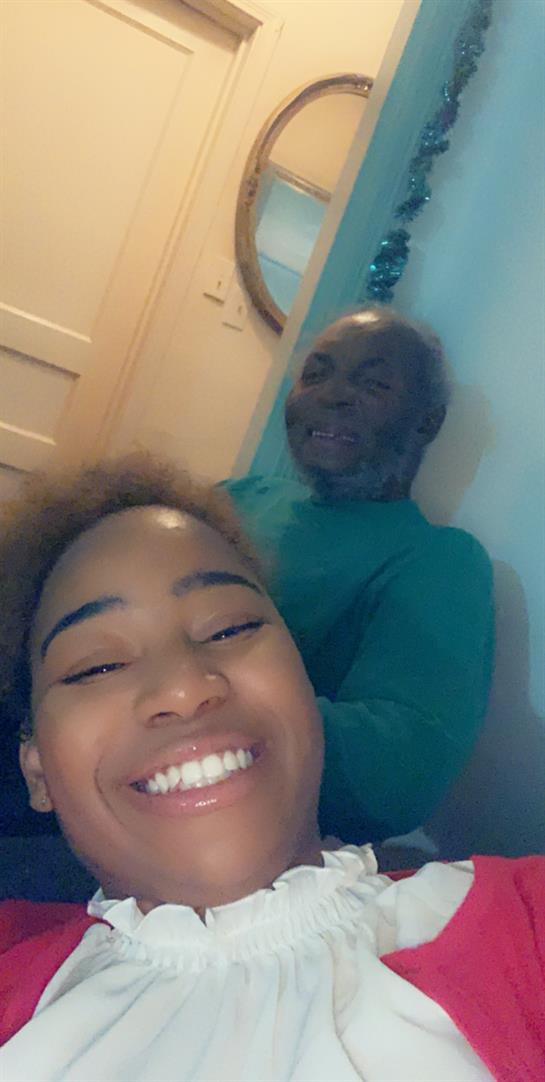 Young girl and elderly man share a cheerful moment together in a warm home environment.