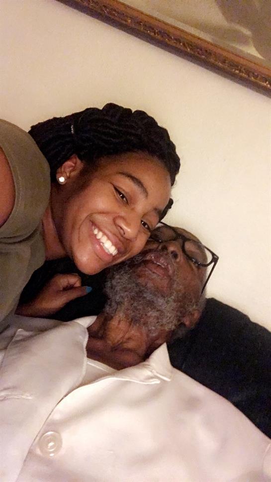 Young woman smiles brightly as she embraces her grandfather at their home, enjoying quality time.