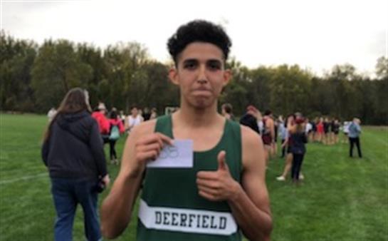 A runner proudly holds a card while giving a thumbs up after finishing at a track meet in Deerfield.