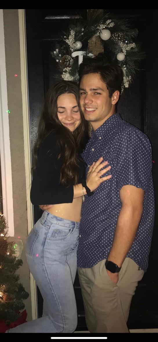 Happy couple embraces warmly, showcasing their connection at a friendly social gathering.