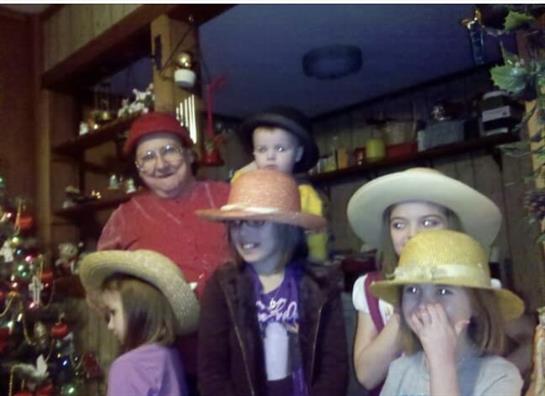 Family gathers in a cozy room, wearing bright hats and sharing lively moments.