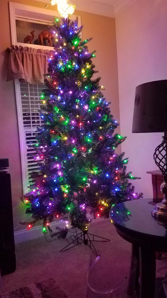 A beautifully decorated Christmas tree shines with multicolored lights in a welcoming living room.