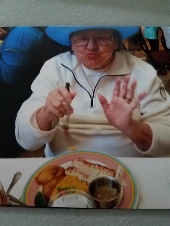An elderly woman prepares to eat her colorful meal at a bustling restaurant filled with patrons.