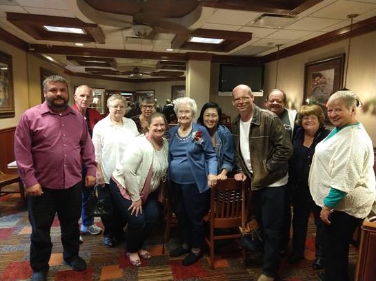 Group of people gathered in a restaurant, smiling and celebrating together with joy and laughter.