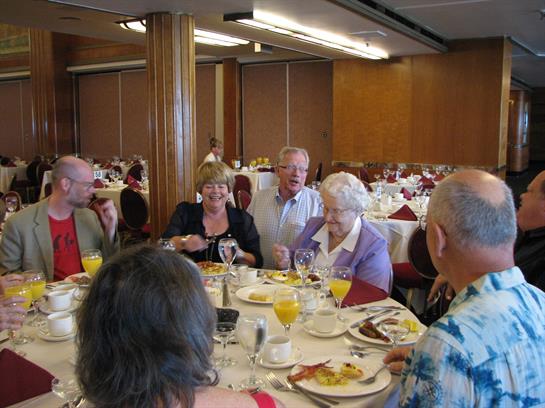Friends gather around a table, enjoying food and drinks while sharing laughter and conversation.
