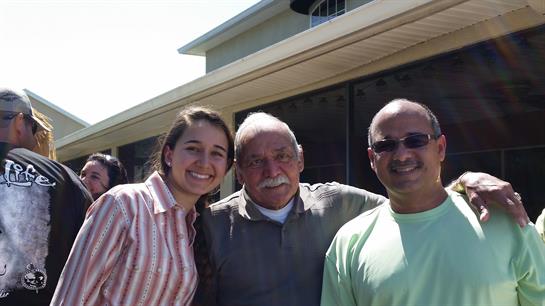 Three people smile in the sun, enjoying warmth and happiness together.