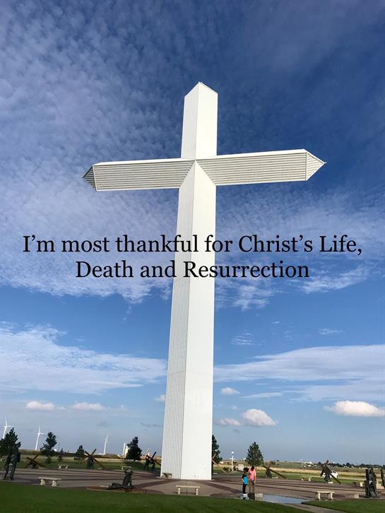 A tall white cross against a blue sky symbolizes gratitude for faith and spirituality.