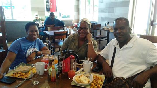 Three friends sit together at a vibrant cafe, enjoying brunch with hearty food and drinks.