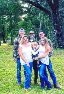 Group of family members smiling and posing together outdoors in a park setting surrounded by nature.