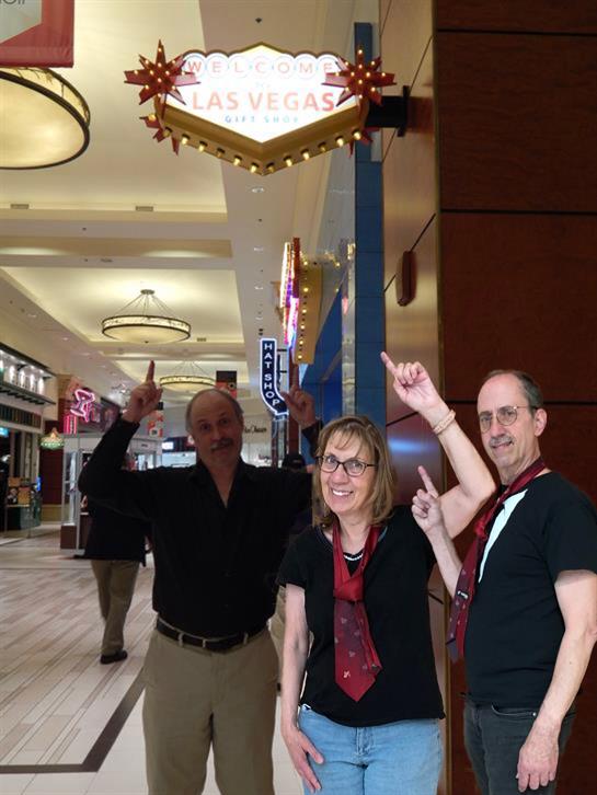 Tourists celebrate in a bustling Las Vegas mall, excitedly pointing at a colorful sign.