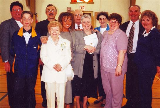 A large family group poses together at a joyful celebration in a community venue.
